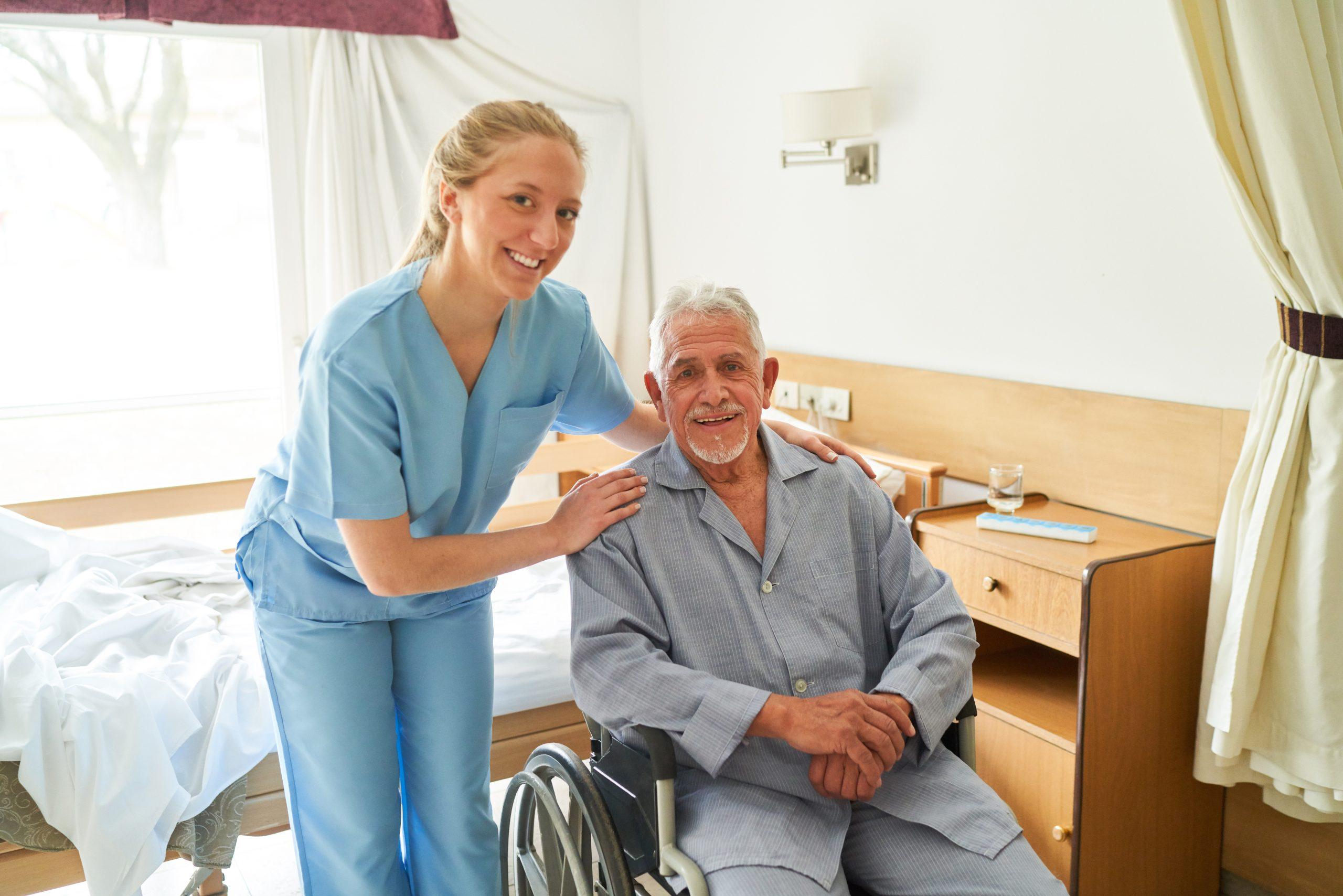 Smiling nurse with elderly man in wheelchair